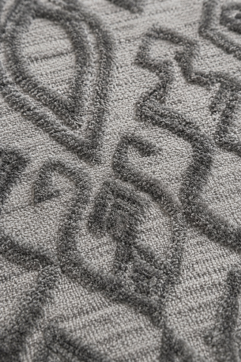 Close-up of the Ash Nomad handloom over hand tufted New Zealand wool rug showcasing raised carved tribal motifs and handcrafted wool texture