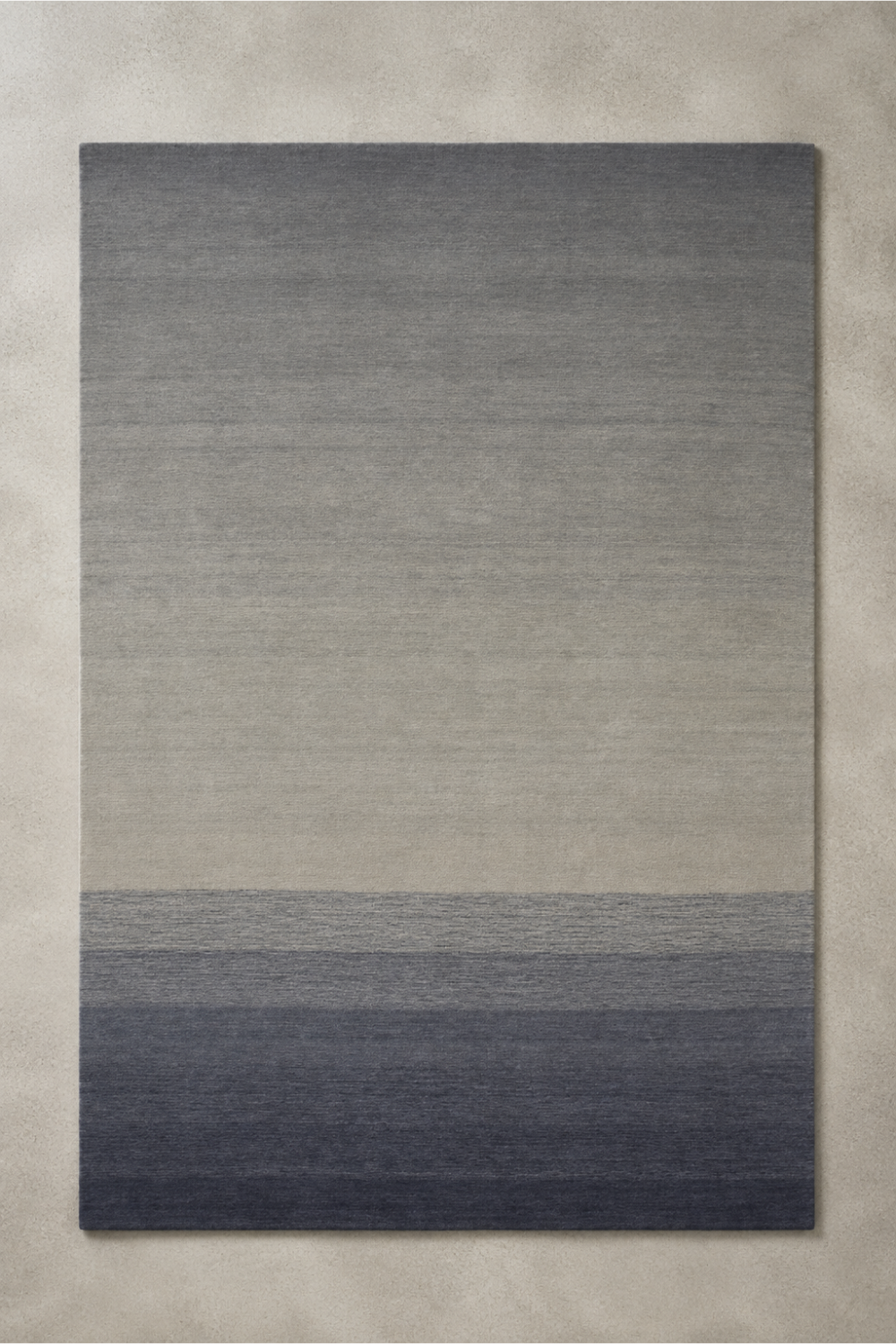 Stone Horizon handloom New Zealand wool ivory and charcoal gradient rectangular area rug on a neutral stone background