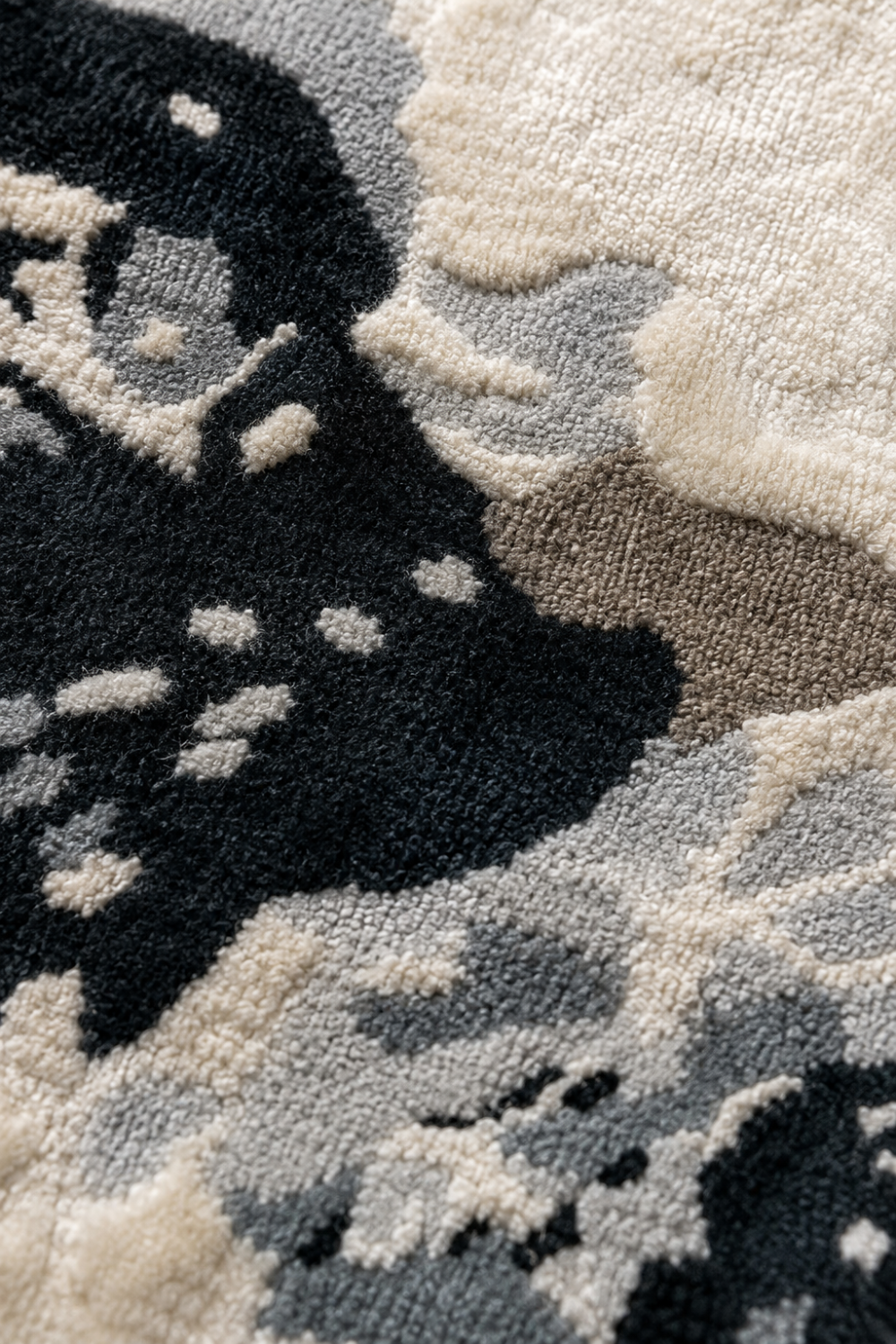 Close-up view of the Stone Veil Round Rug highlighting its handcrafted high-low texture, soft ivory fibres, layered grey detailing, and charcoal accents.